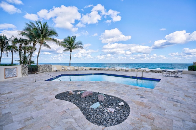 view of swimming pool featuring a water view and a patio