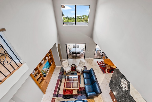 living room with built in features, a towering ceiling, and light tile flooring