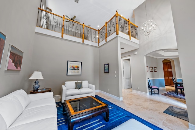 living room with light tile flooring, ornamental molding, a high ceiling, and an inviting chandelier