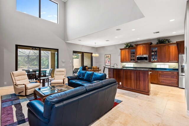 living room featuring light tile flooring, sink, and a high ceiling