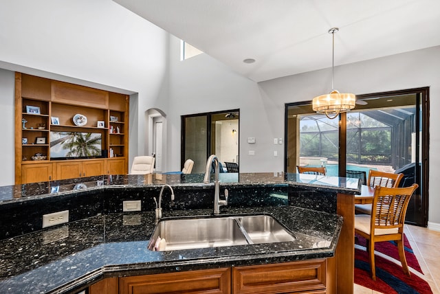 kitchen with pendant lighting, sink, dark stone countertops, a chandelier, and light tile flooring