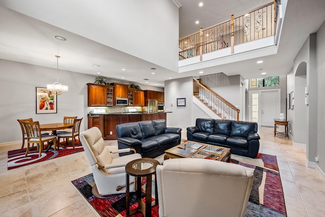 living room featuring a chandelier, sink, light tile floors, and a high ceiling