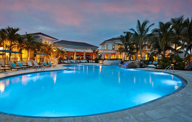 pool at dusk featuring a patio area and pool water feature