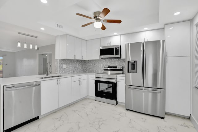 kitchen featuring pendant lighting, ceiling fan, sink, appliances with stainless steel finishes, and white cabinetry