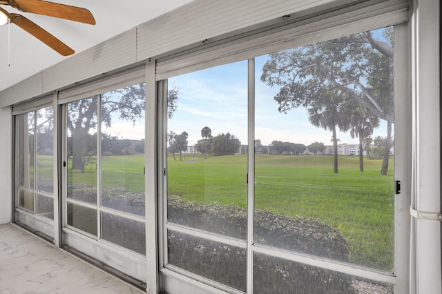 unfurnished sunroom featuring ceiling fan and a healthy amount of sunlight