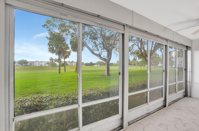 unfurnished sunroom featuring ceiling fan