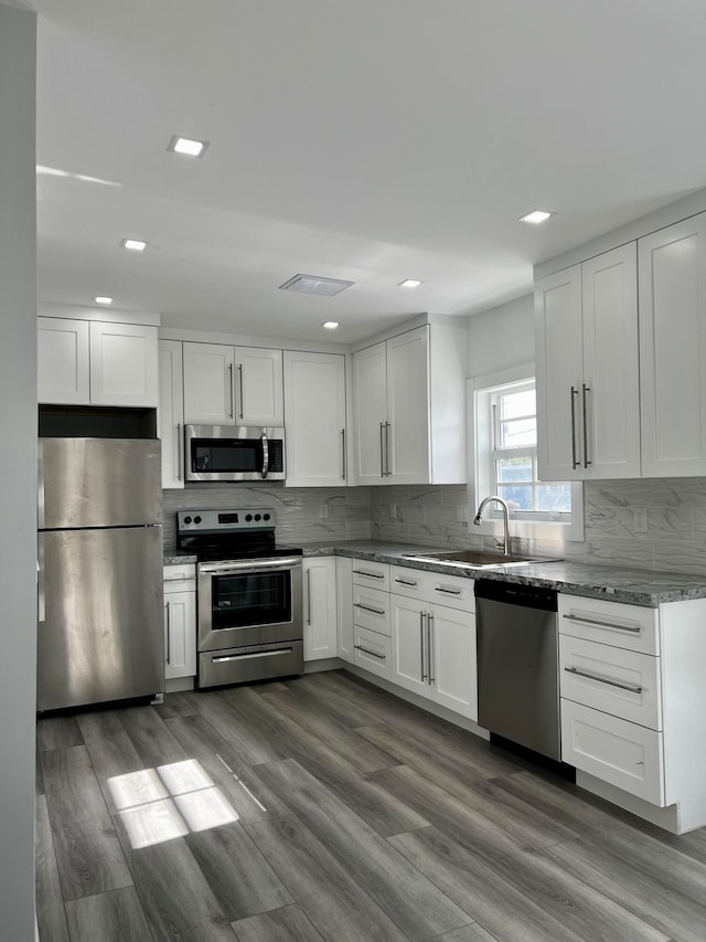 kitchen with white cabinetry, stainless steel appliances, hardwood / wood-style flooring, and sink