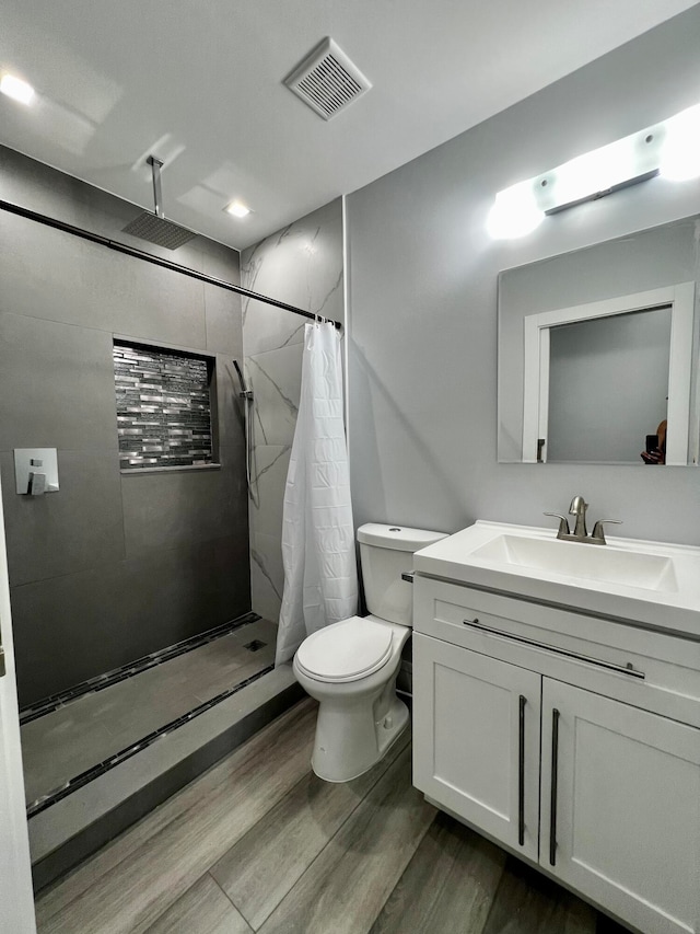 bathroom featuring toilet, large vanity, wood-type flooring, and a shower with curtain