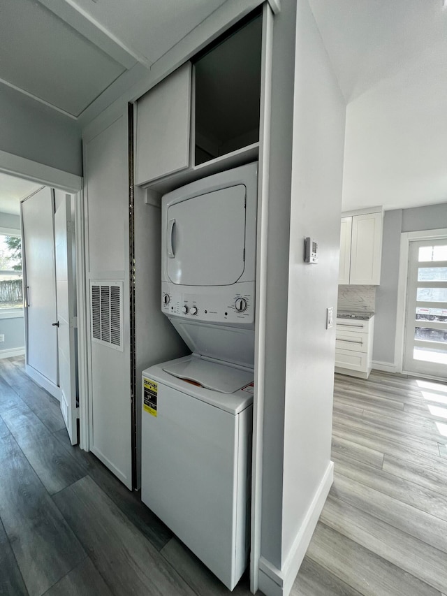 laundry room featuring light hardwood / wood-style flooring and stacked washer and dryer