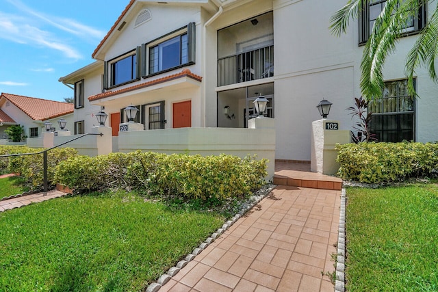 property entrance featuring a balcony and a yard