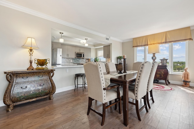 dining space with wood-type flooring and crown molding