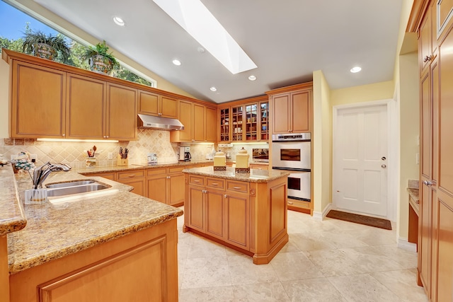 kitchen with light stone countertops, backsplash, stainless steel double oven, light tile flooring, and a kitchen island