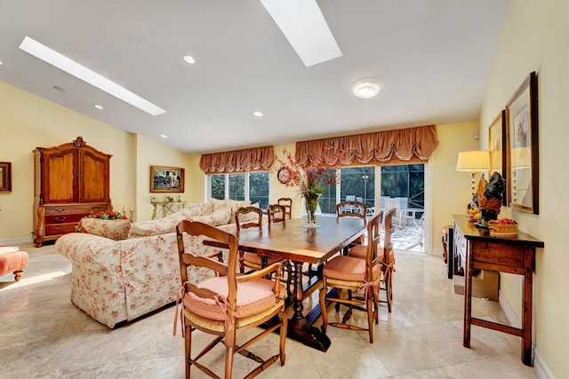 dining space featuring vaulted ceiling with skylight and light tile floors