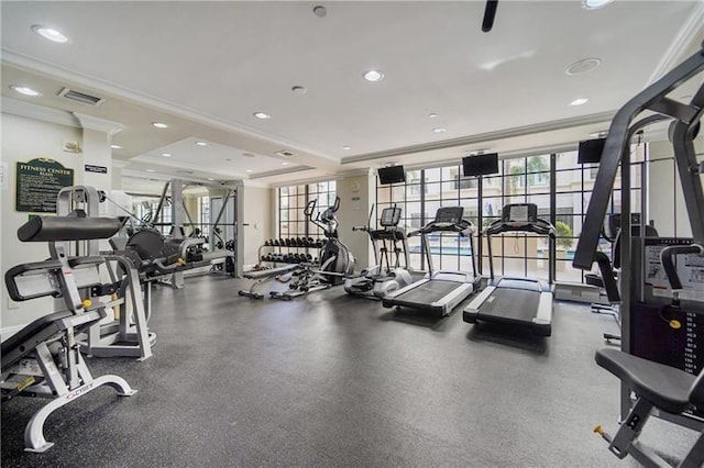 gym featuring a tray ceiling and ornamental molding