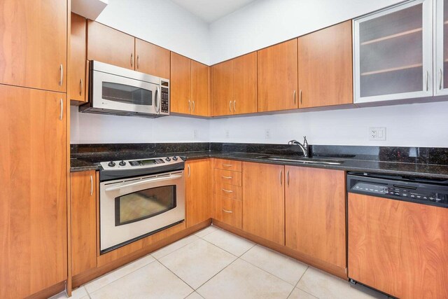 kitchen with light tile patterned flooring, appliances with stainless steel finishes, sink, and dark stone counters