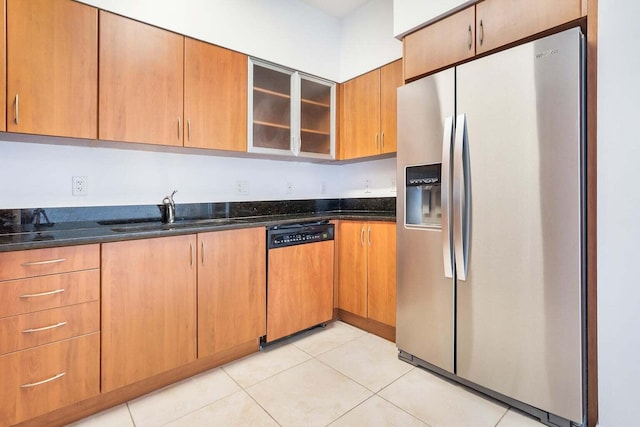 kitchen featuring sink, dark stone countertops, light tile patterned flooring, and stainless steel appliances