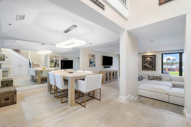 dining area featuring a tray ceiling and light hardwood / wood-style flooring