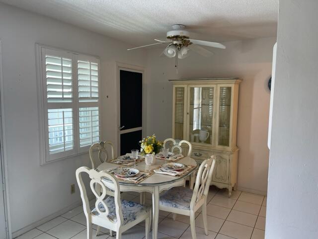 dining area with a textured ceiling, ceiling fan, and light tile flooring