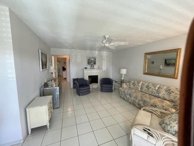 living room featuring light tile floors, ceiling fan, and a textured ceiling