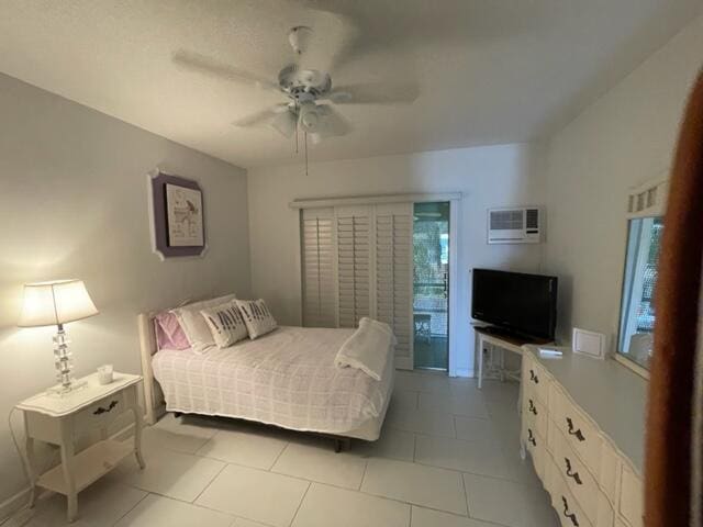 tiled bedroom with ceiling fan and a wall unit AC