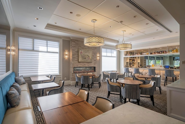 dining area featuring a tray ceiling, dark colored carpet, and bar area