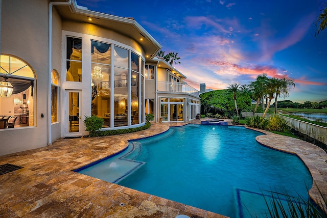 pool at dusk featuring an in ground hot tub and a patio