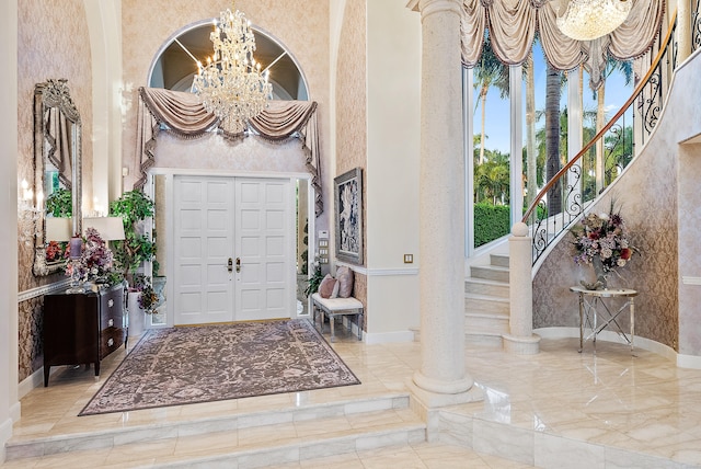 entryway featuring a high ceiling, decorative columns, light tile floors, and an inviting chandelier