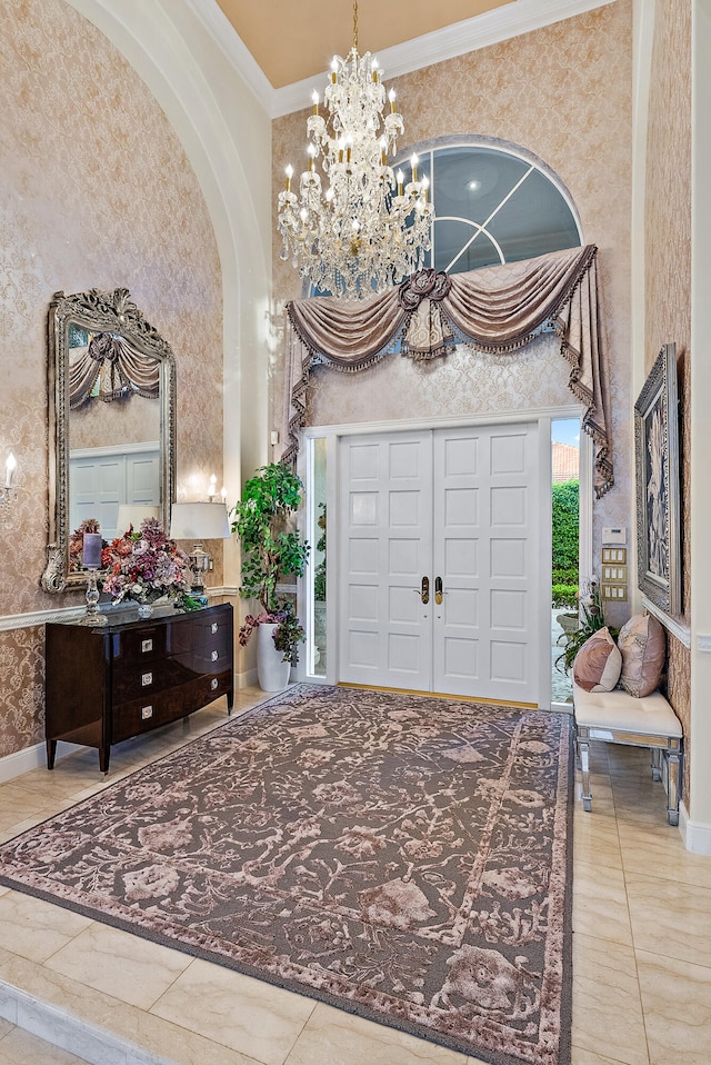 tiled foyer with a high ceiling, a chandelier, and ornamental molding