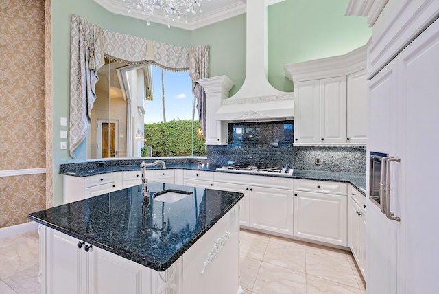 kitchen with dark stone counters, crown molding, a kitchen island, a chandelier, and white cabinetry