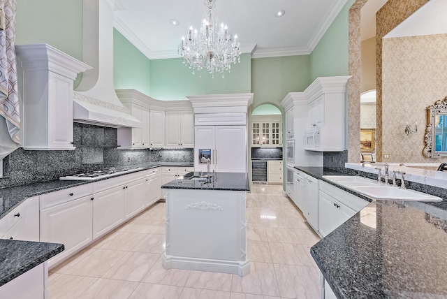 kitchen featuring white cabinets, a notable chandelier, premium range hood, and a center island