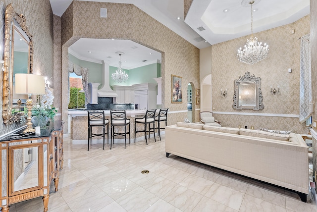 tiled living room with ornamental molding, a notable chandelier, and a tray ceiling