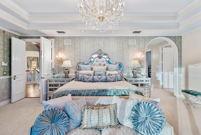 carpeted bedroom with a notable chandelier, a tray ceiling, and ornamental molding