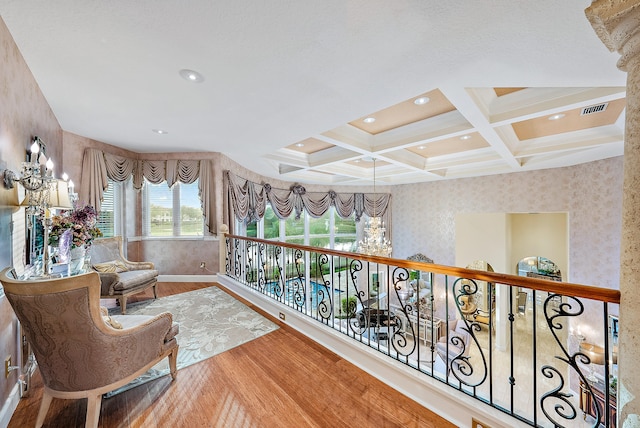 hallway with coffered ceiling, light hardwood / wood-style floors, a notable chandelier, and beam ceiling