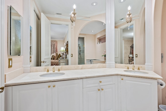 bathroom with crown molding, large vanity, ornate columns, and dual sinks