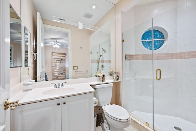 bathroom featuring toilet, vanity with extensive cabinet space, ceiling fan, and a shower with door