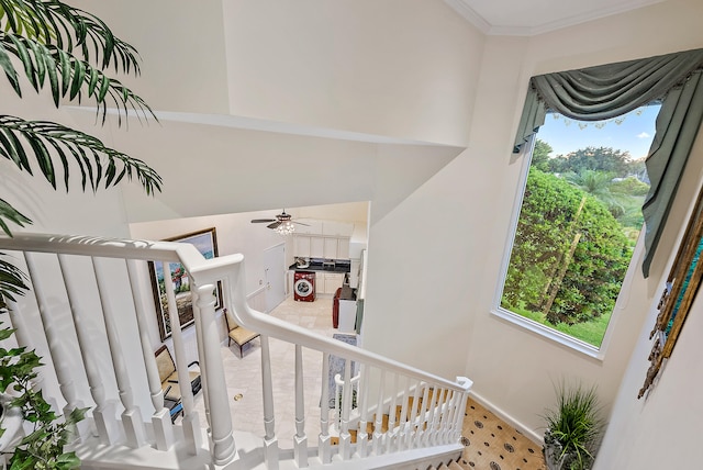 stairway with plenty of natural light, crown molding, ceiling fan, and a high ceiling