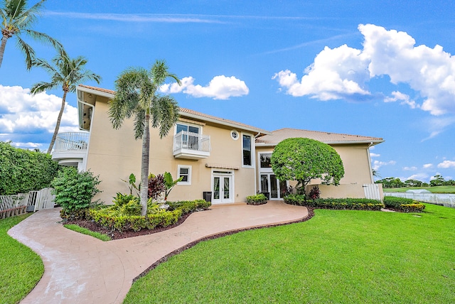 view of front of house featuring a front lawn, a balcony, french doors, and central AC unit