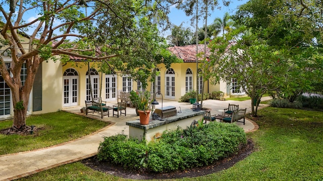 rear view of property featuring a yard, a patio area, and french doors