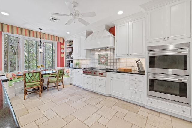 kitchen with ceiling fan, appliances with stainless steel finishes, premium range hood, white cabinets, and tasteful backsplash