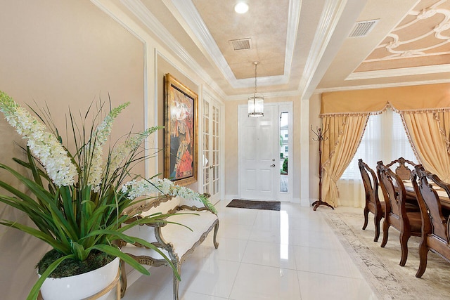 tiled entrance foyer with ornamental molding and a tray ceiling