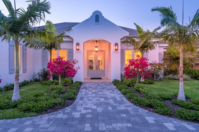 exterior entry at dusk featuring a lawn