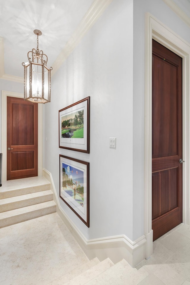 corridor featuring light tile flooring, ornamental molding, and a notable chandelier