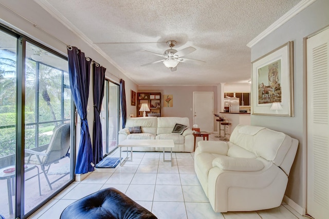 living room with ceiling fan, light tile patterned flooring, a textured ceiling, and ornamental molding