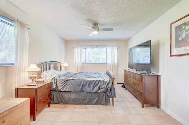 bedroom with ceiling fan, light tile patterned flooring, and a textured ceiling