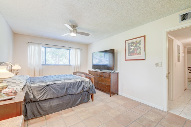 bedroom with ceiling fan, light tile patterned floors, and a textured ceiling