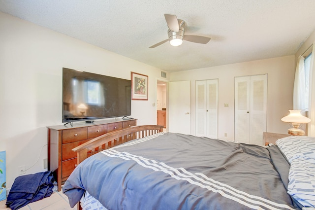 bedroom with multiple closets, ceiling fan, and a textured ceiling