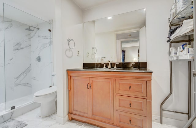 bathroom with vanity, toilet, and a tile shower