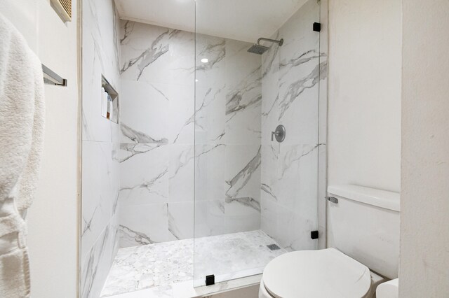 bathroom featuring toilet and a tile shower