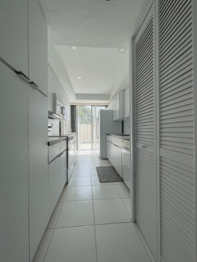 interior space with white appliances, white cabinetry, and light tile floors