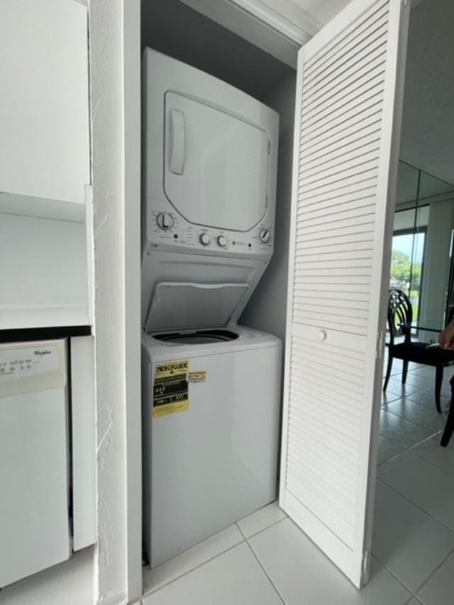 laundry area featuring light tile flooring and stacked washer / drying machine